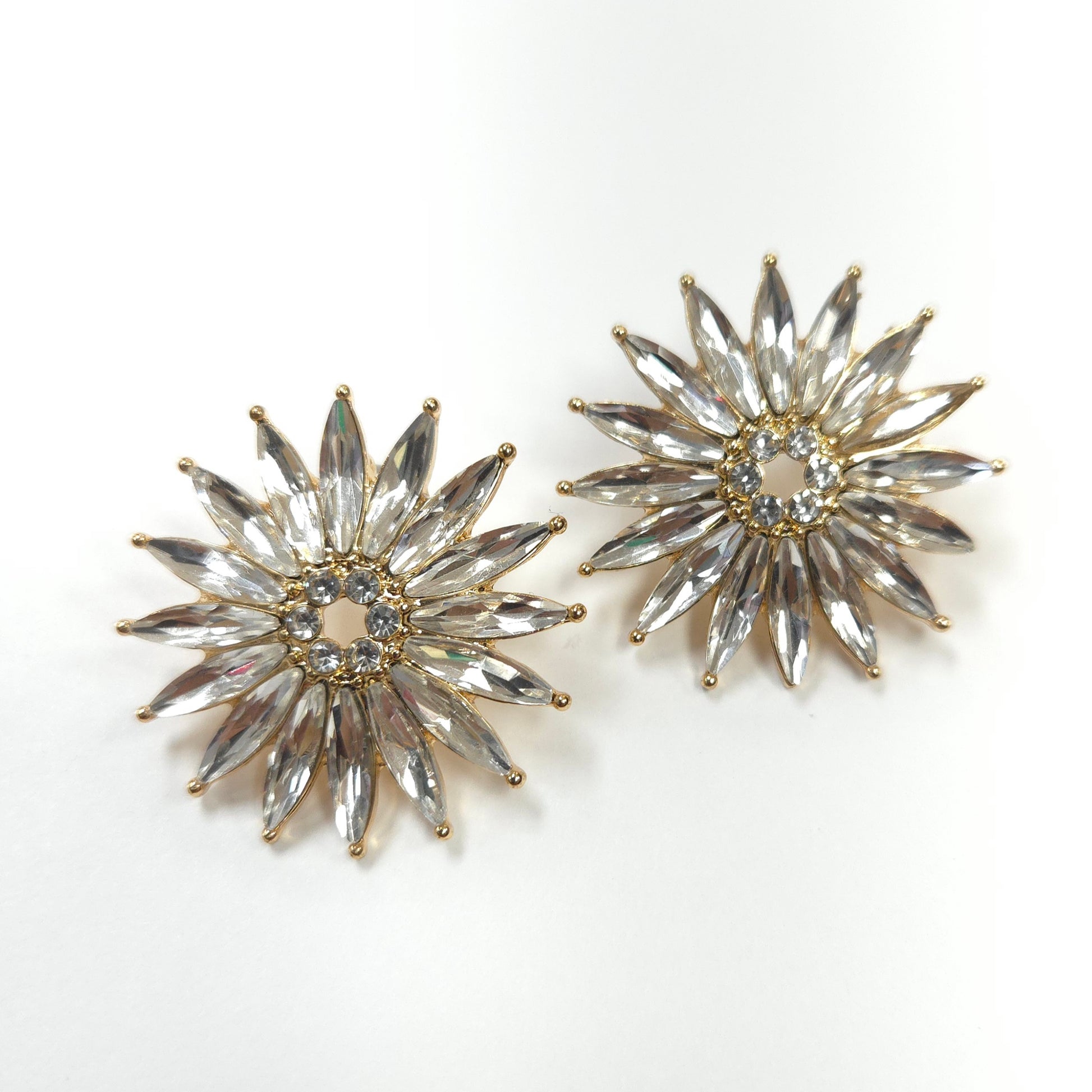 Pair of star-shaped earrings with clear gemstones on a white background