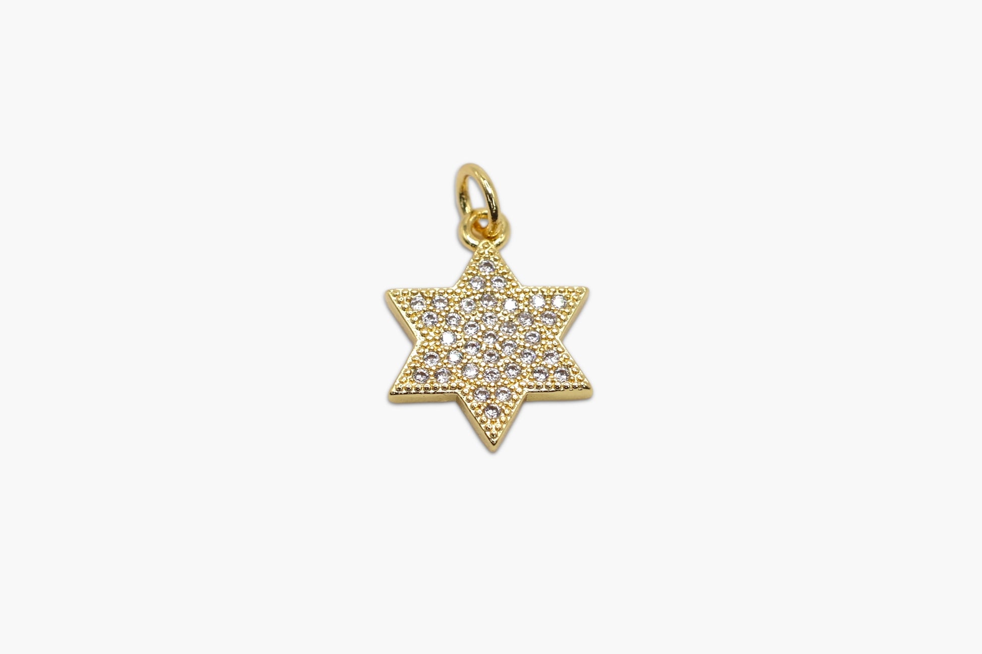 Gold star-shaped pendant with embedded stones on a white background