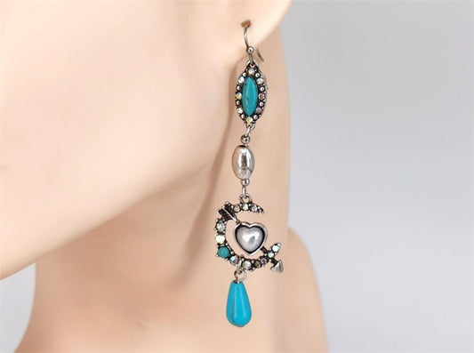 Earring with turquoise stones and silver heart design on a mannequin ear.